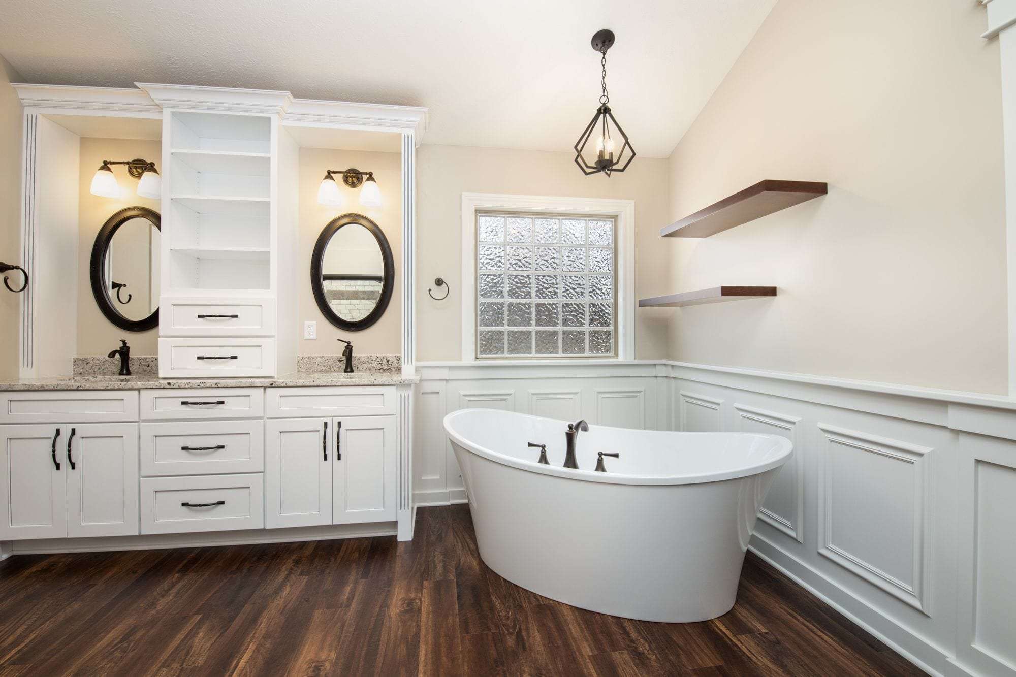 traditional white bathroom with dark wood flooring and large white tub