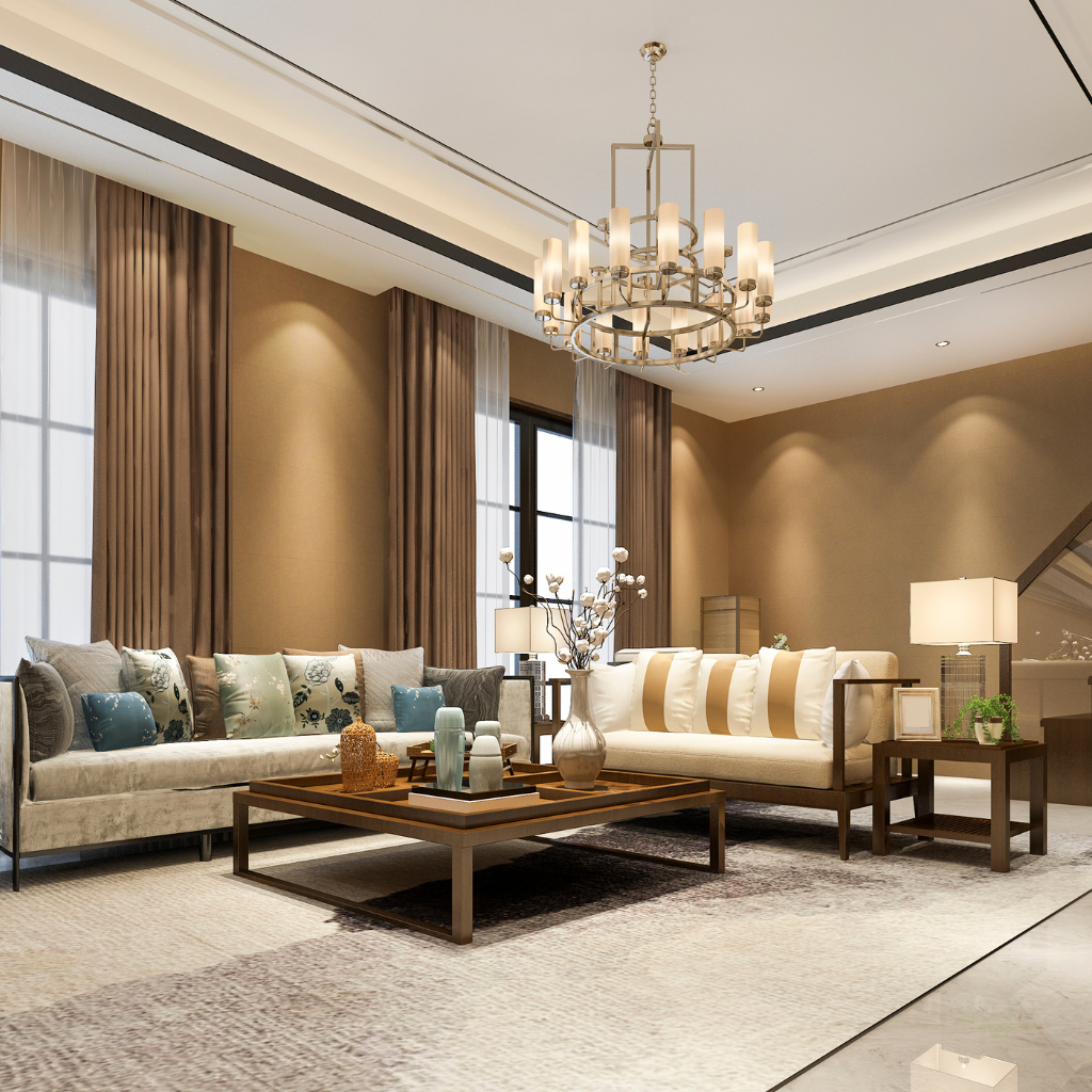 A modern living room with a beige color scheme features two sofas with assorted cushions, a wooden coffee table with decorative items, and a large chandelier. The space is well-lit by natural light from two windows with floor-length curtains.